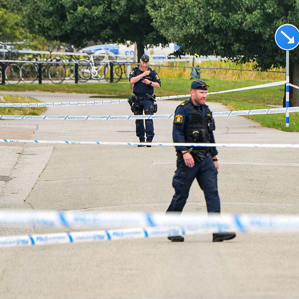 Två poliser står upp och det är avspärrningsband över gatan