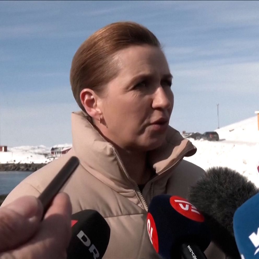 Person intervjuas utomhus, mikrofoner från olika mediekanaler syns i förgrunden. Snö täcker marken.