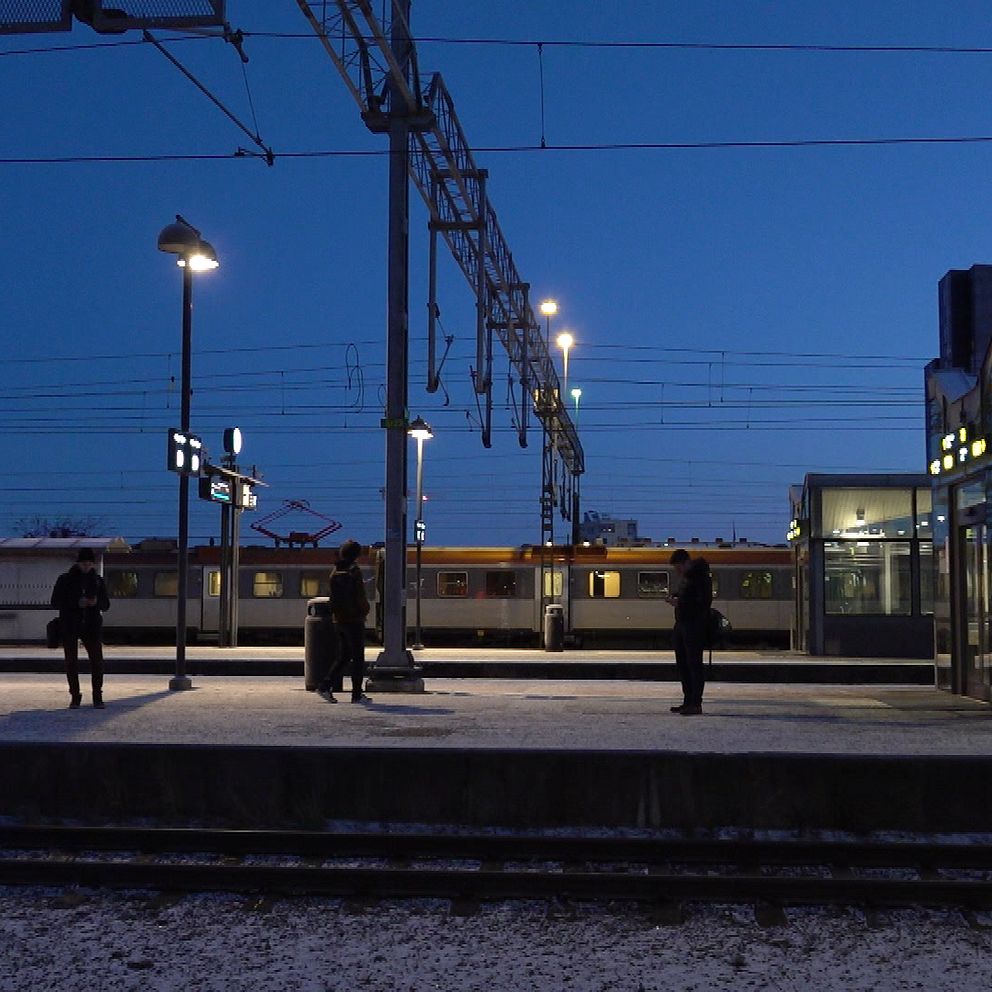 En vinterkväll på en tågstation med snö på plattformen. Mörknaden i bakgrunden ger en stillsam atmosfär.