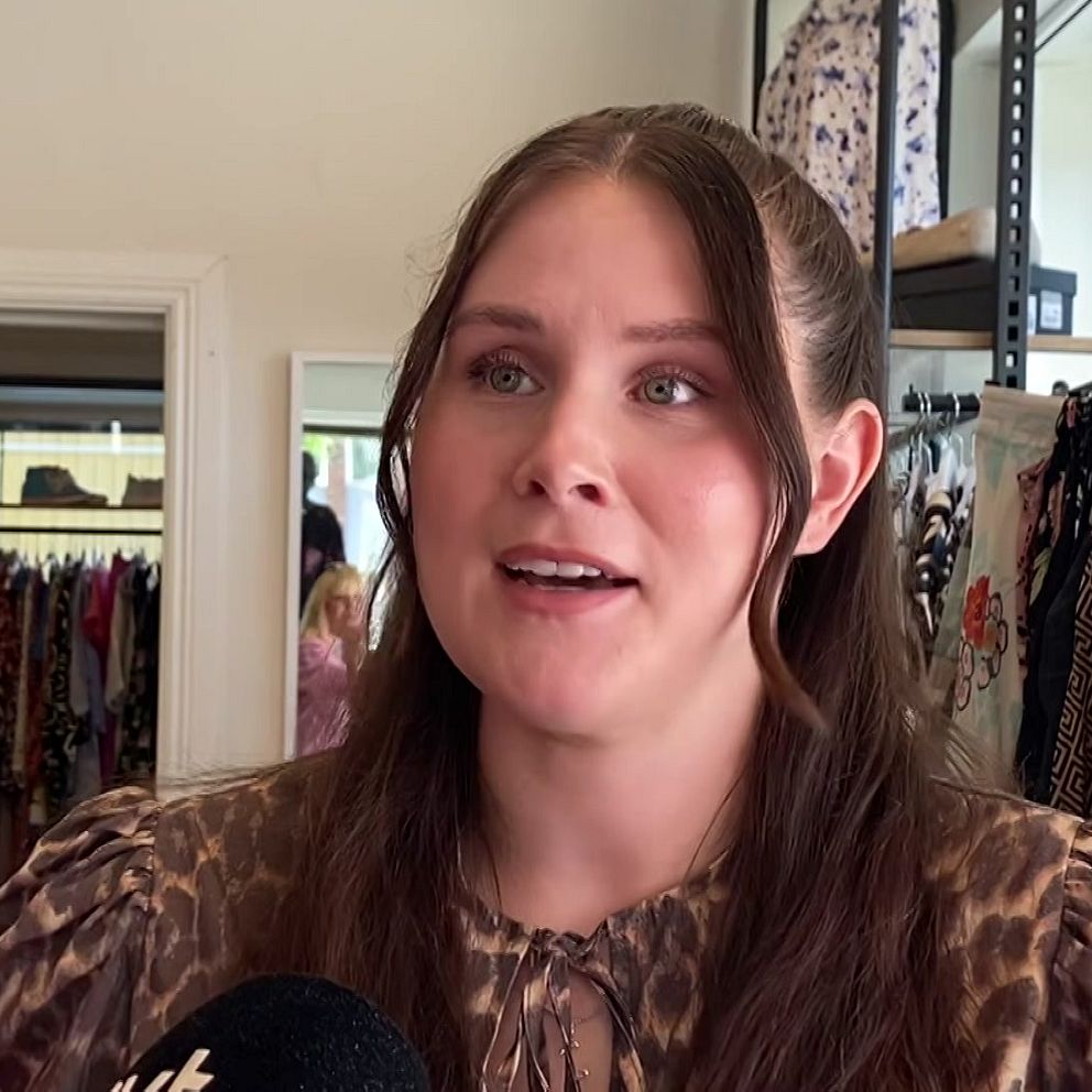 Moa Thorneus i second hand-butik med kläder synliga i bakgrunden.