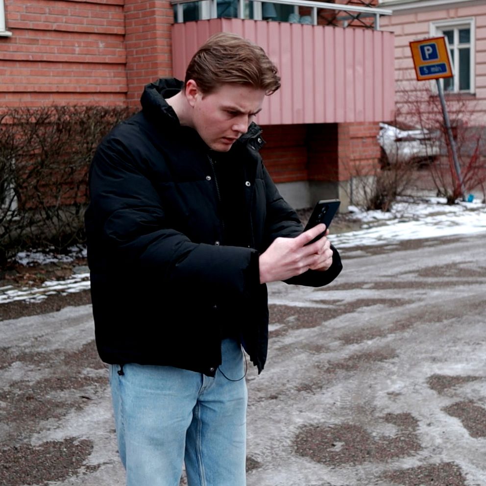 Man som står framåtlutad med mobil i händerna