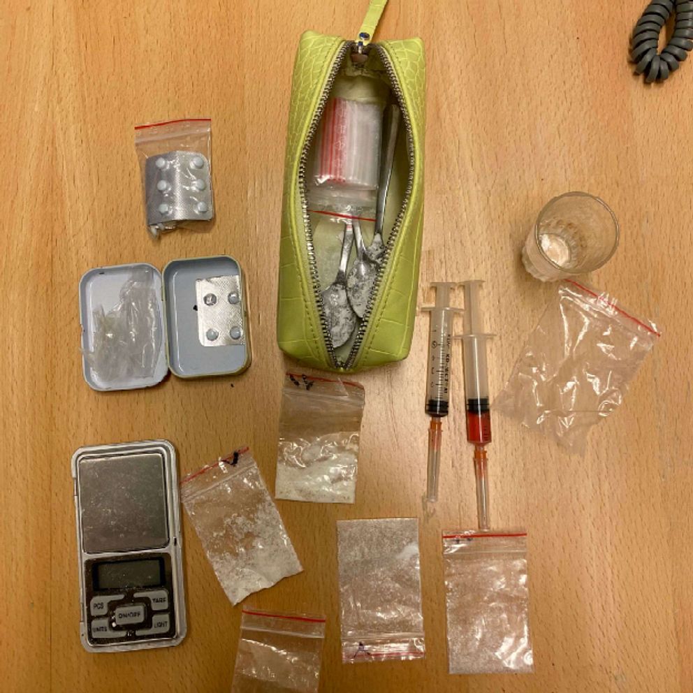 Narkotikarelaterade föremål på ett bord: våg, sprutor, plastpåsar med vitt pulver och en grön väska.