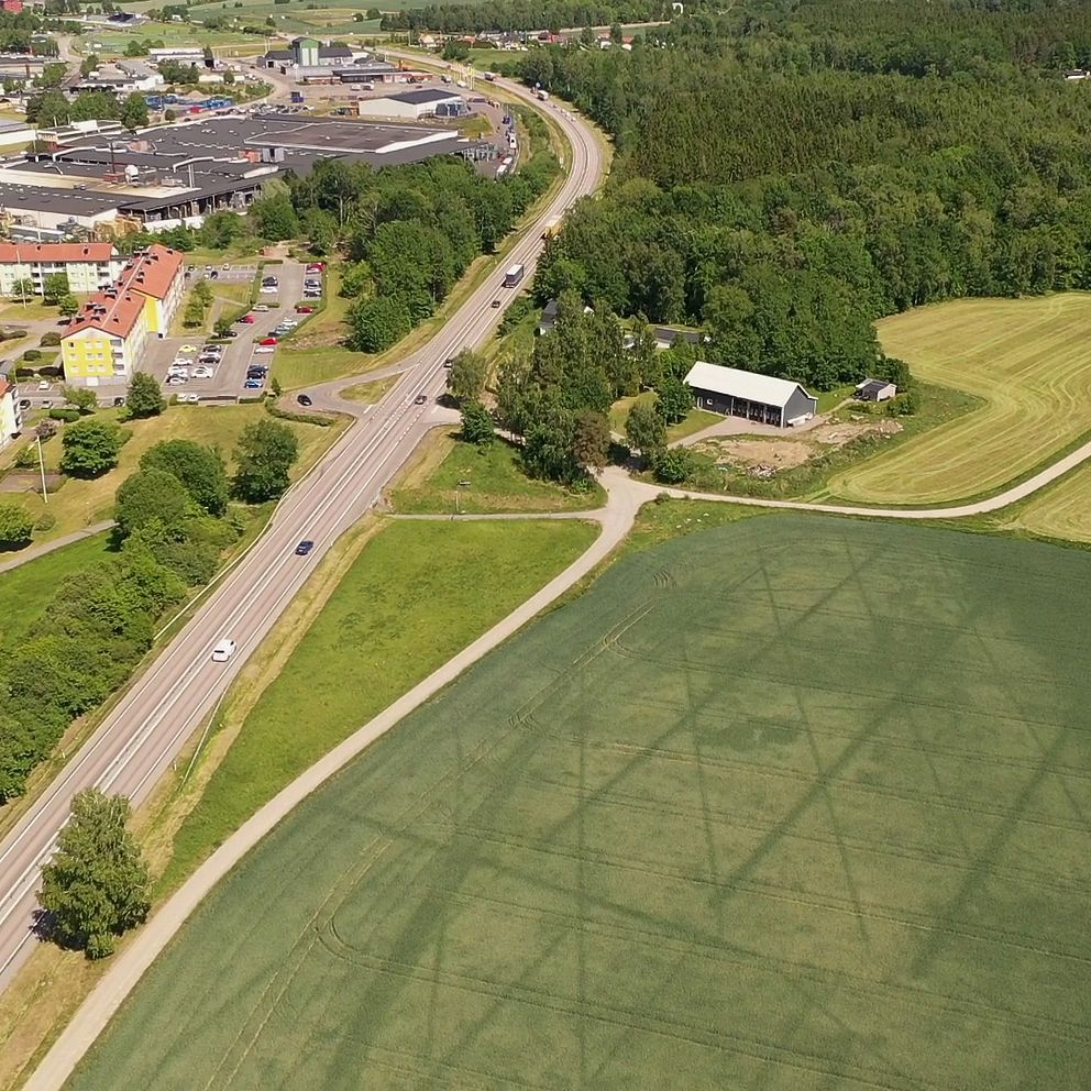 Drönarbild över Skara. Stadsbebyggelse till vänster om E20, landsbygd direkt till höger om E20.