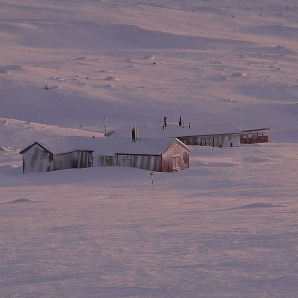 Snötäckt landskap med ett ensamt hus i skymningsljus.
