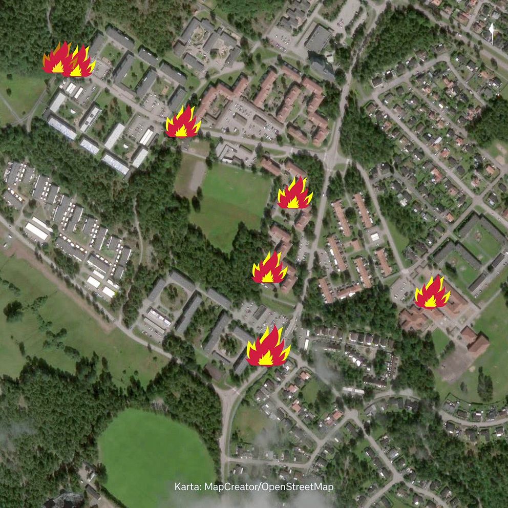 Satellitbild över en stadsmiljö med flera röda eldsymboler som markerar specifika platser. Området domineras av byggnader omgivna av grönområden och vägar. Eldsymbolerna indikerar potentiella brandrisker eller platser för händelser relaterade till eld.