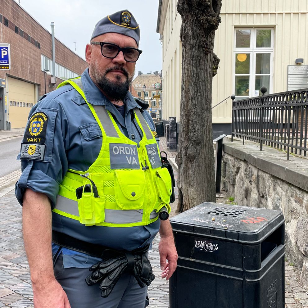 En manlig ordningsvakt står bredvid en soptunna i centrala Helsingborg.
