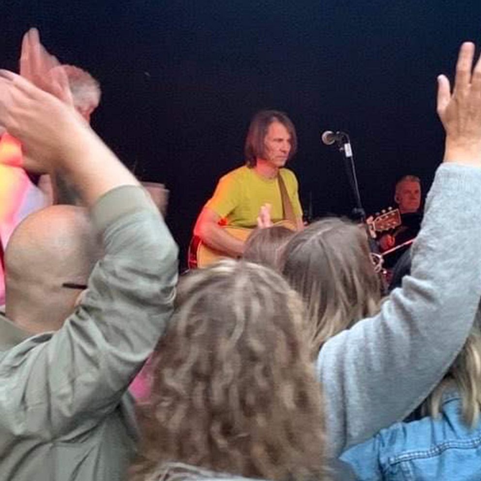 vy över publikens huvuden och viftande händer mot scen där Jakob Hellman spelar gitarr i en gul tshirt