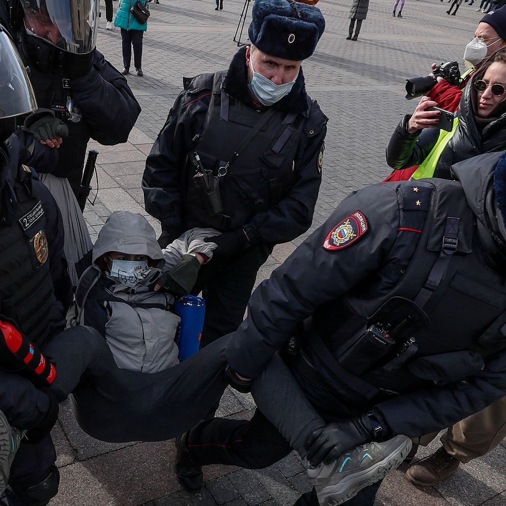 En person grips av ryska poliser i Moskva, de bär personen i benen och armarna från en gata där protester mot Rysslands invasion av Ukraina hållits.