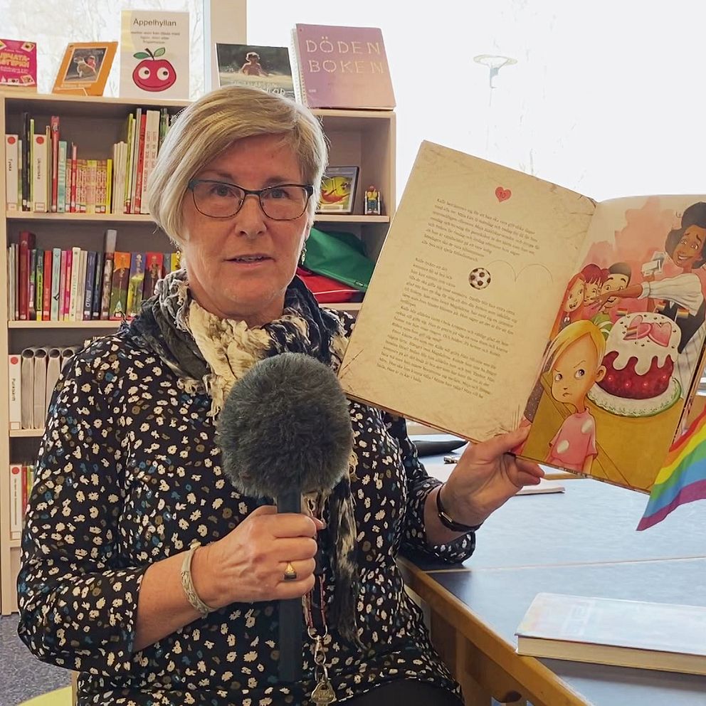 På bilden håller bibliotekarie Carin Carlström i Sveg på Svegs bibliotek i Härjedalen upp en bok som passar på regnbågshyllan.
