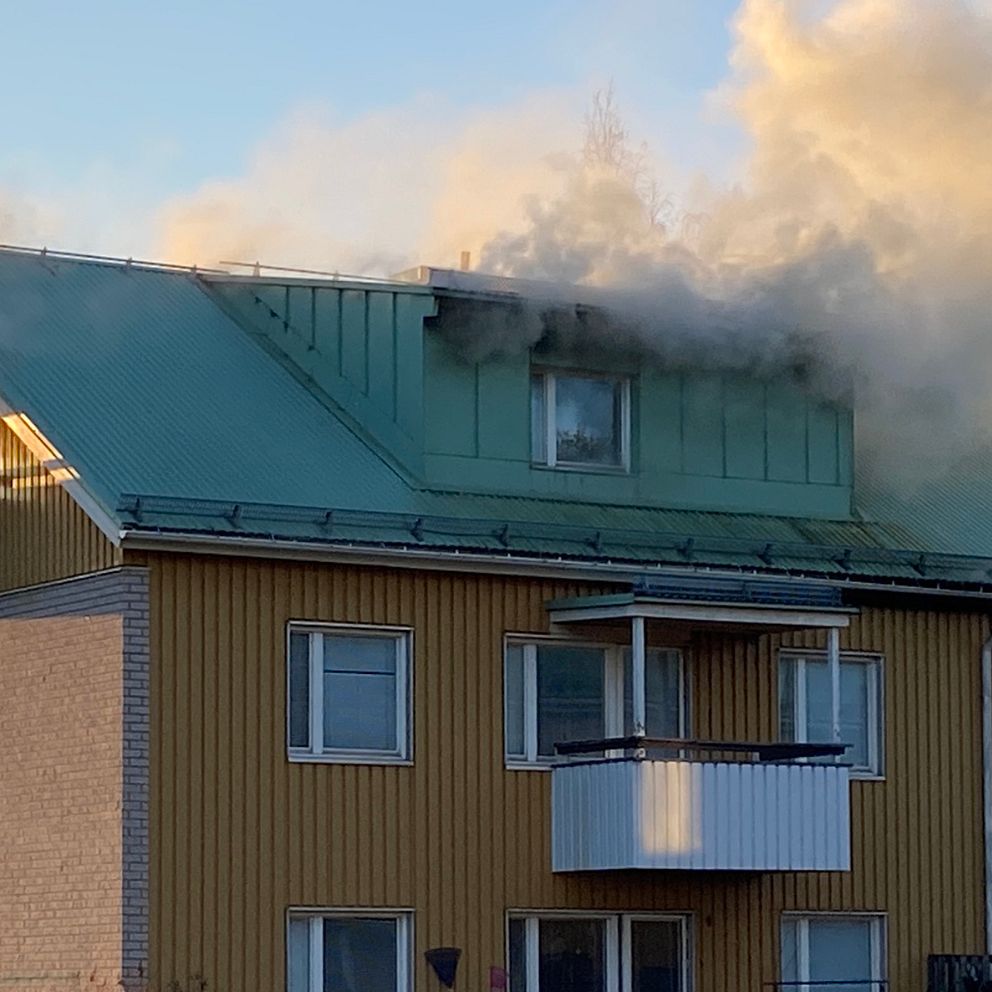 brandmän på kran vid gaveln av ett rykande bostadshus