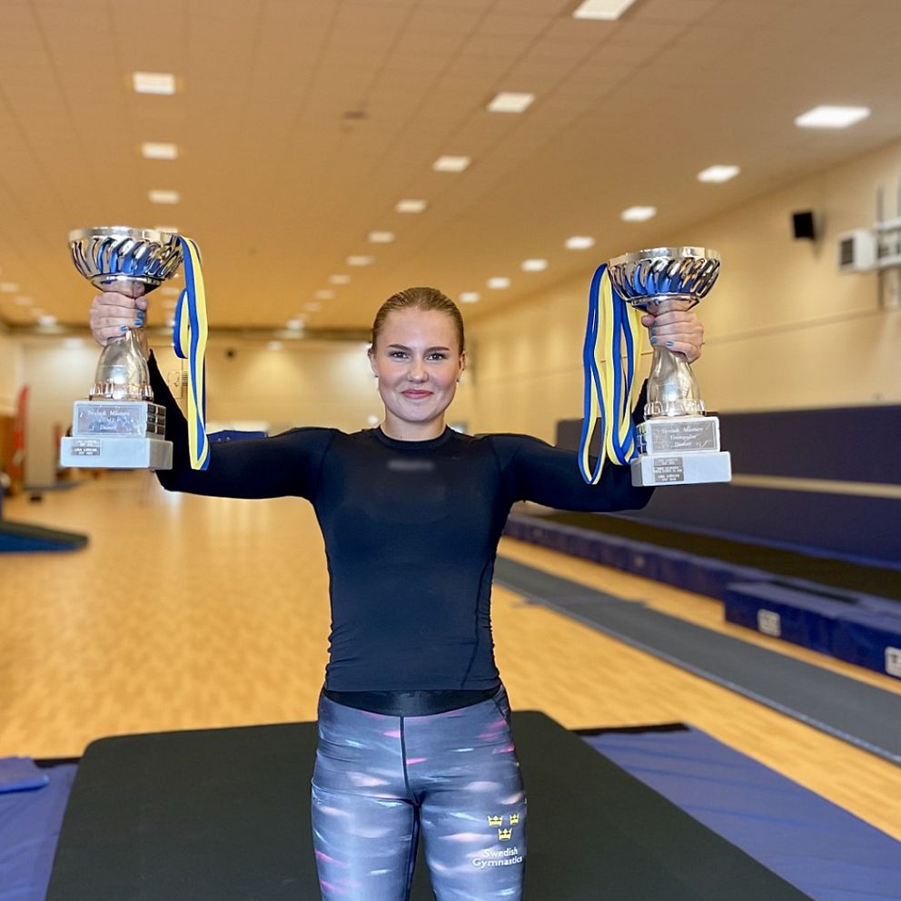 Tuva Stjärnborg från Klippans Gymnastikkrets håller upp två pokaler och fem guldmedaljer i SM i trampolin och DMT som hölls i Lidköping.