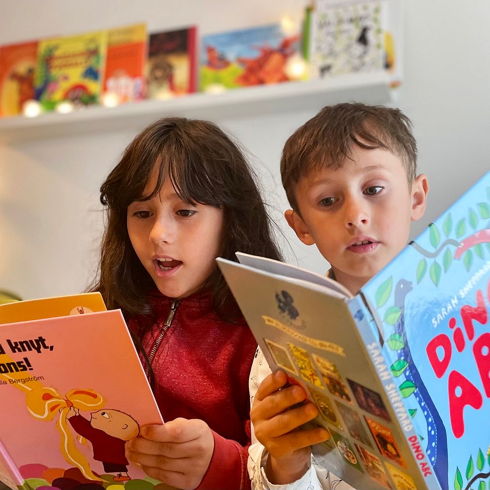 Inne i läskojan på planteringen i Helsingborg sitter syskonen Elsa, 8 år, och Viktor, 6 år, och läser varsin bok. Viktor lär sig läsa genom projektet Familjen läser.