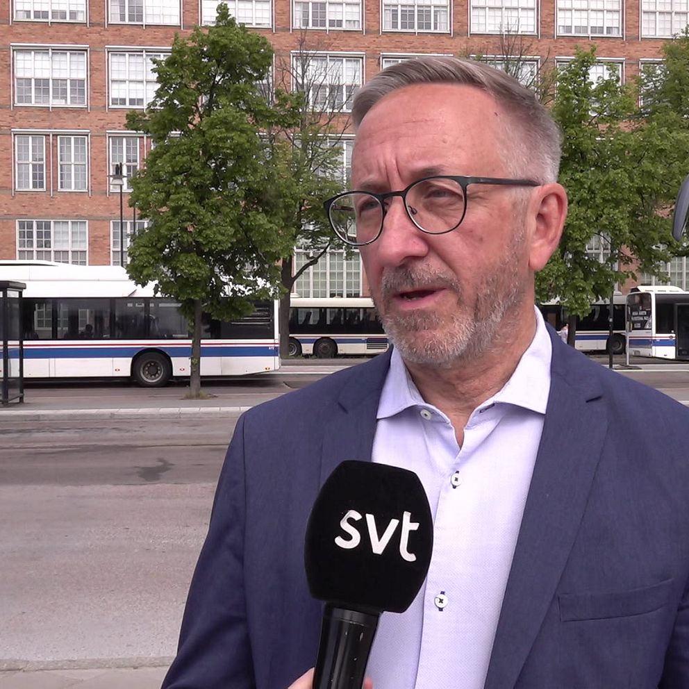 Man klädd i kaval och vit skjorta står framför centralstationen i Västerås med bussar i bakgrunden