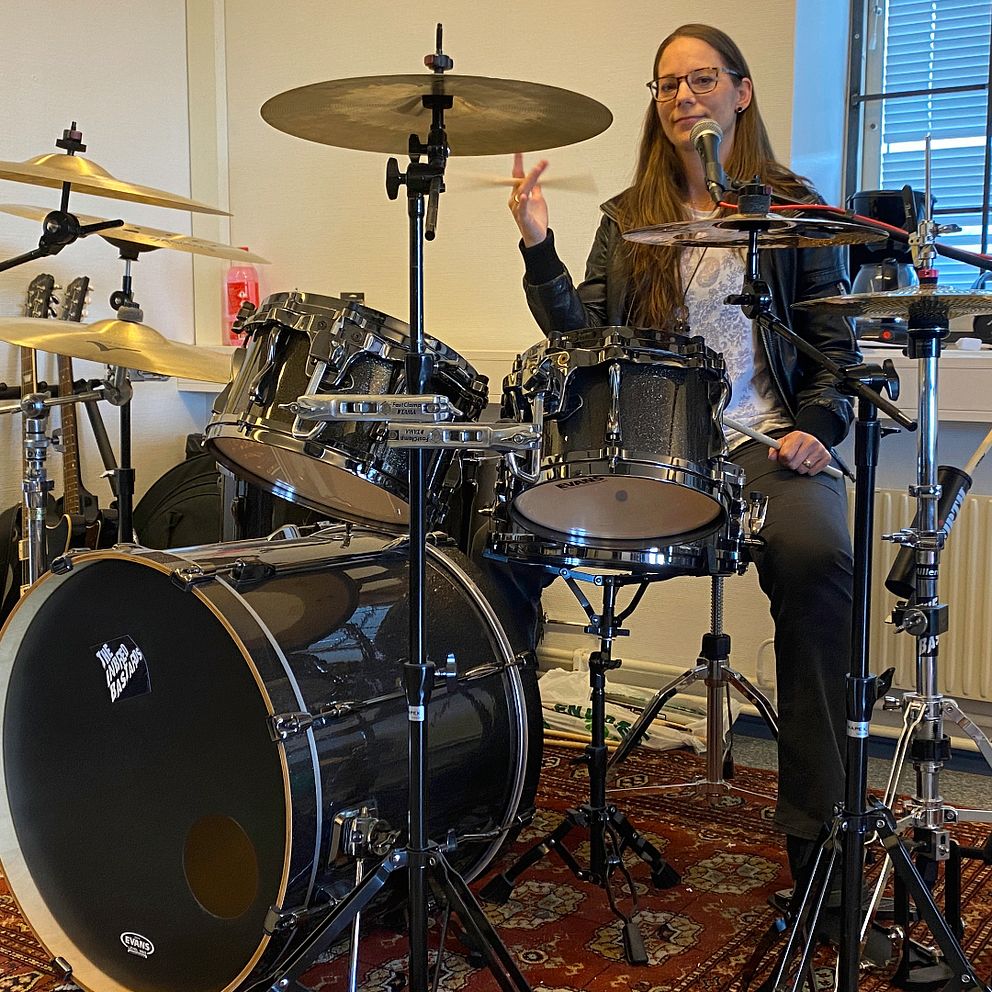 Musikern Linda Theodoridis sitter vid ett trumset och snurrar med ena handen på en trumpinne.