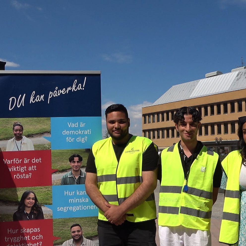 fyra stycken demokratisommarjobbare framför en affish. På torget i Härnösand.