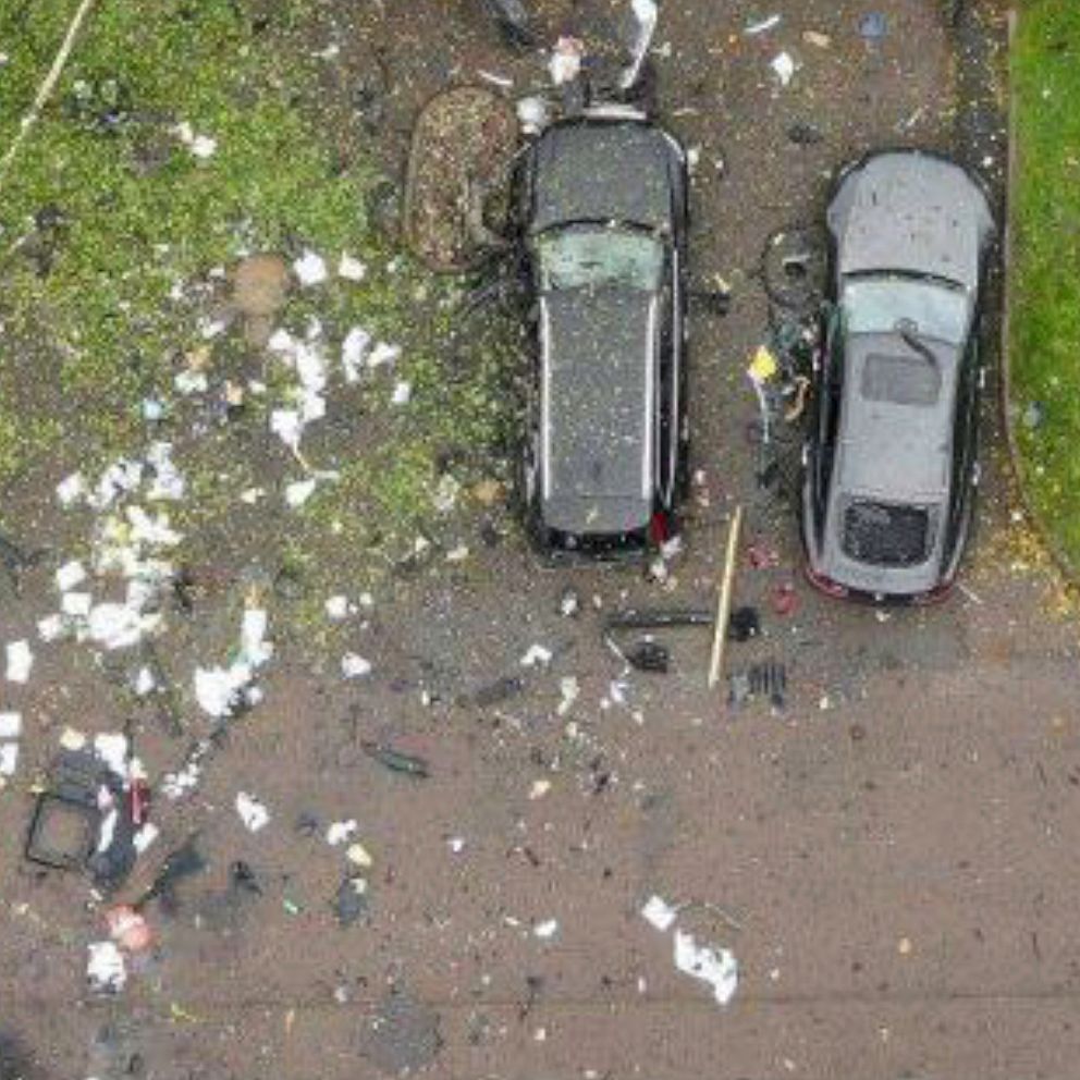 Två bilar står parkerade på en uppfart medan den tredje bilen har blivit till småskrot efter en explosion.