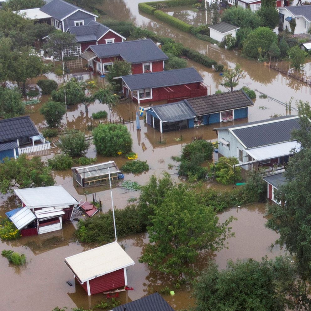 Översvämmat bostadsområde med vägar och trädgårdar täckta av vatten.