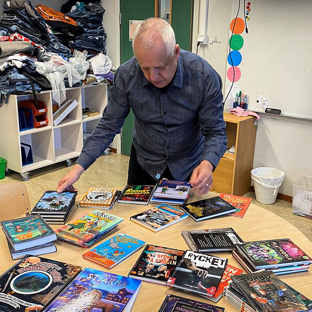 Jyrki Suominen, biblioteksassistent på Hallsbergs bibliotek, framför skolans böcker på ett bord.
