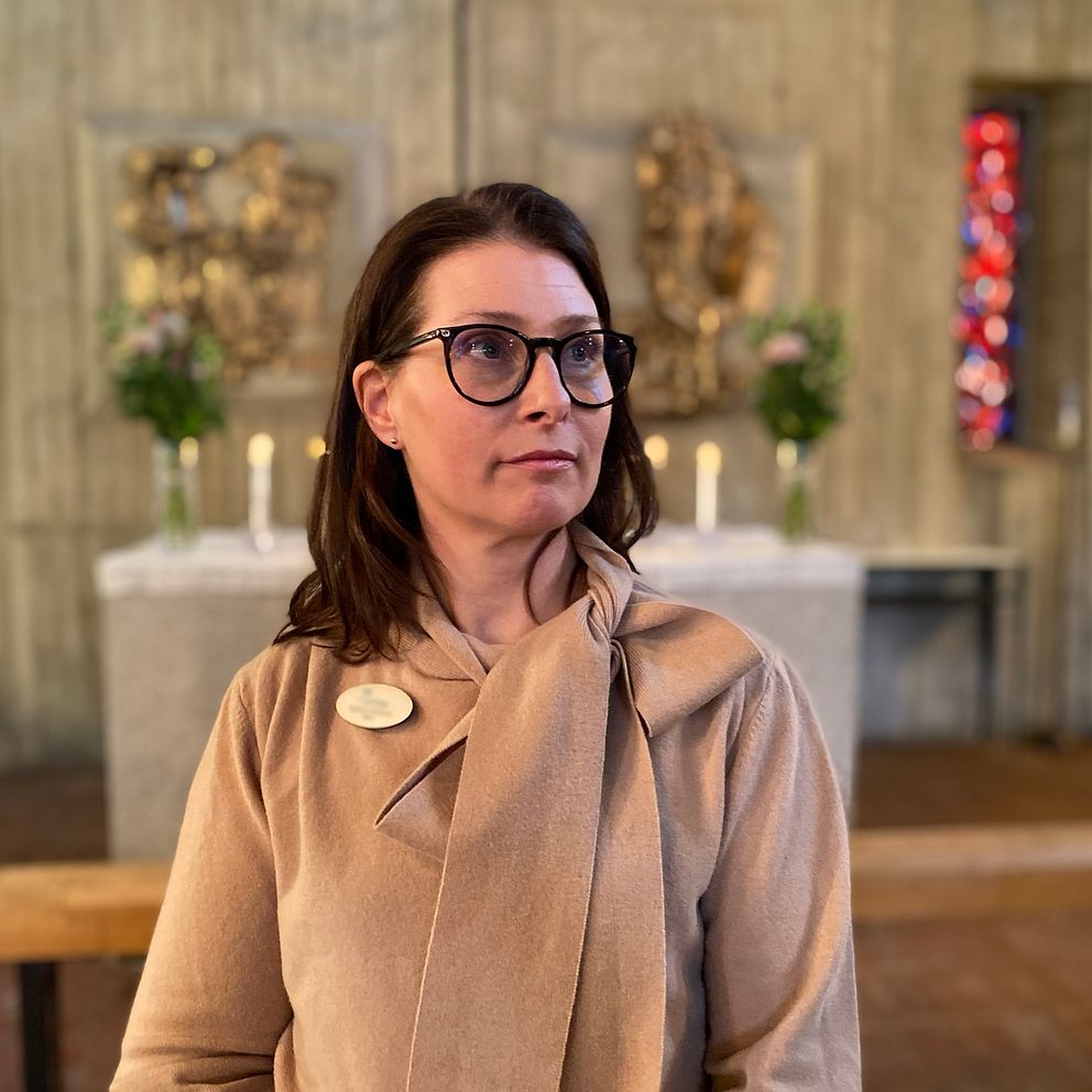 Kvinna står framför altaret i en kyrka och inväntar minnesstund.