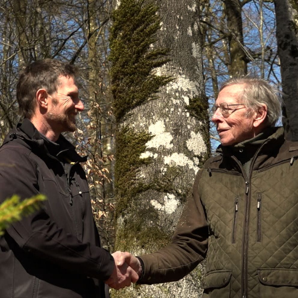 Johan Johnmark och Lennart Olsson skakar hand i skogen vid markbyte till naturreservat