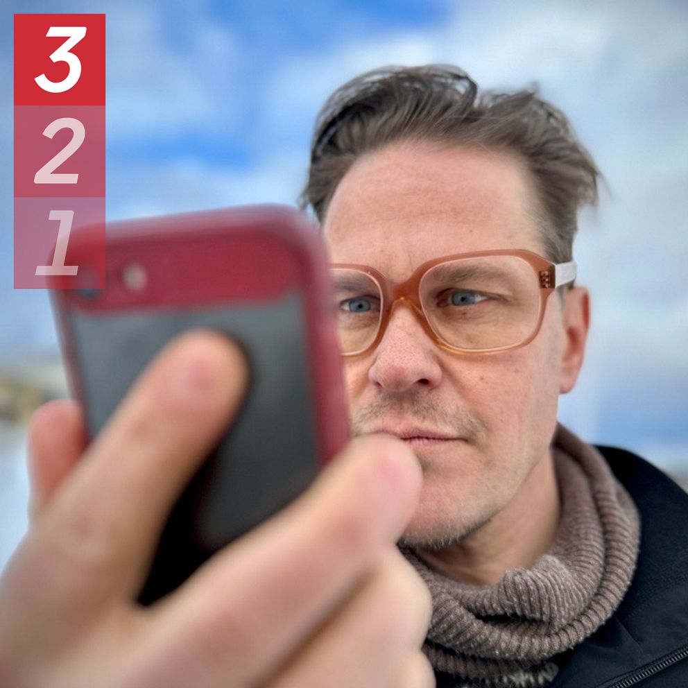 SVT:s reporter Lari Honkanen stirrar på sin mobilskärm. Han har på sig ett par glasögon.