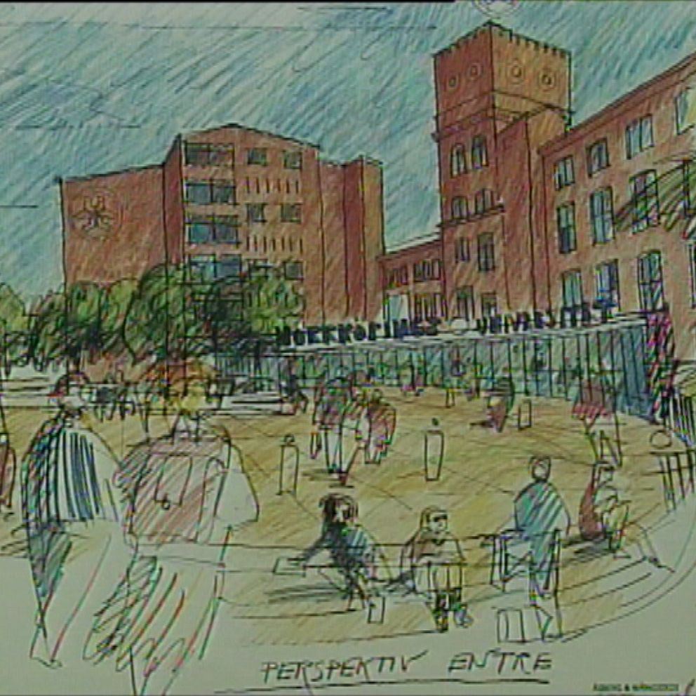 Skiss av en stadsbild med fokus på en plats i stadsrummet som omger en byggnad. Det som ska bli Campus Norrköping. I förgrunden syns människor som promenerar och samlas på en öppen yta med träd och bänkar. I bakgrunden finns en hög byggnad med torn som står i kontrast till de lägre strukturerna runt omkring, under en blå himmel med lätta moln. Texten ”PERSPEKTIV – ENTRÉ” är synlig i nedre hörnet.