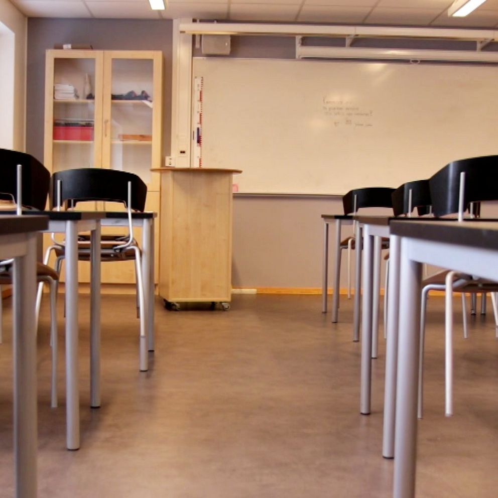 Tomt klassrum med stolar och bord riktade mot en vit tavla.