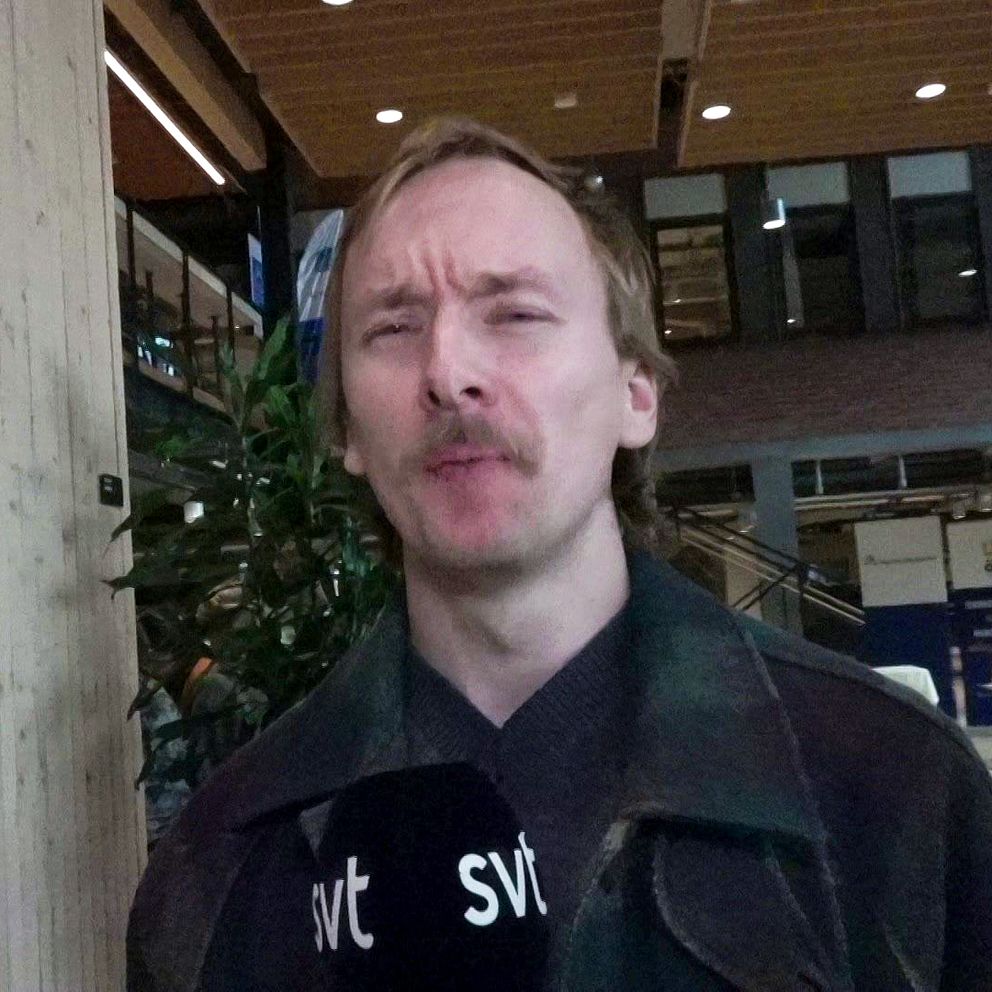 Reporter står med halvöppen mun och har precis ätit en bit mat, han grimaserar.