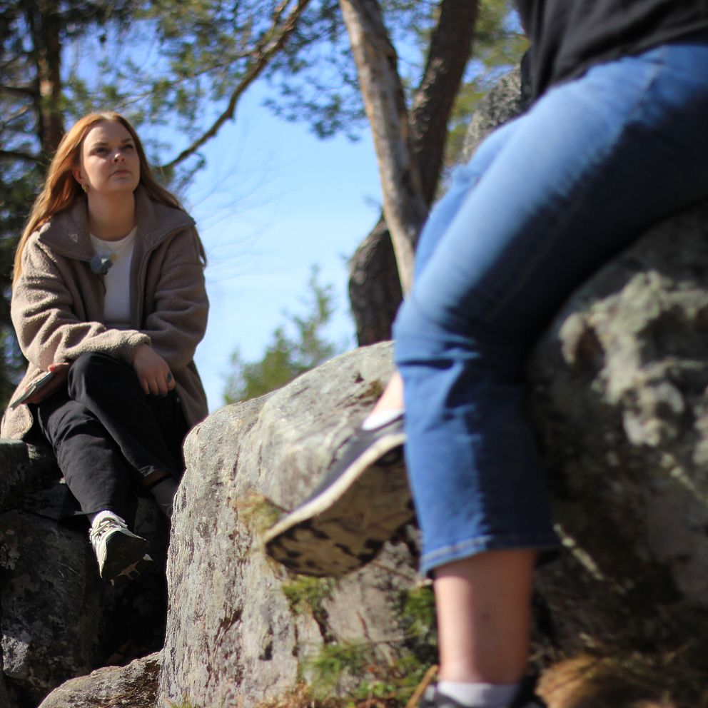 Två kvinnor sitter på en klippa.