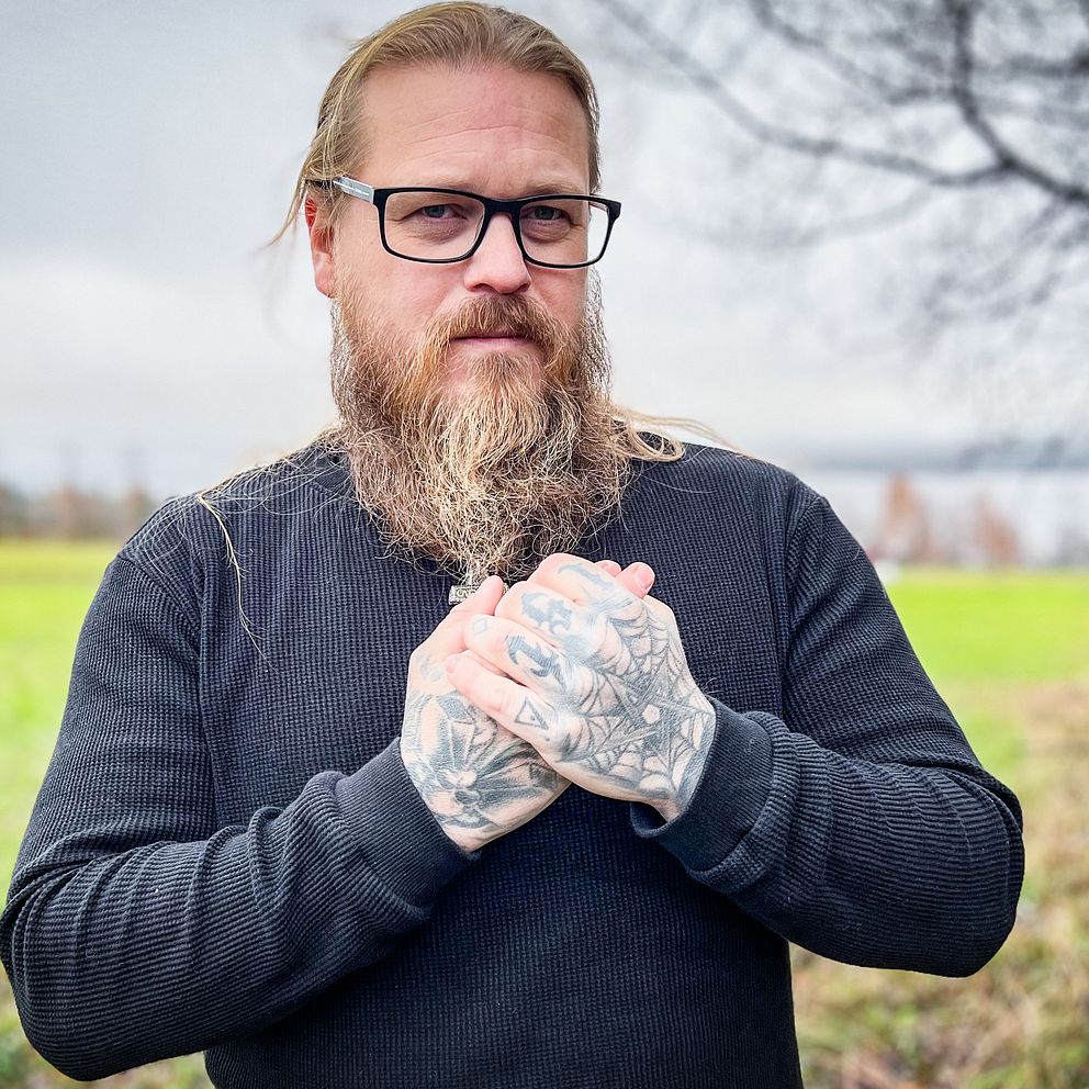 En man med långt skägg och tatuerade händer har drabbats av vibrationsskador som betongarbetare