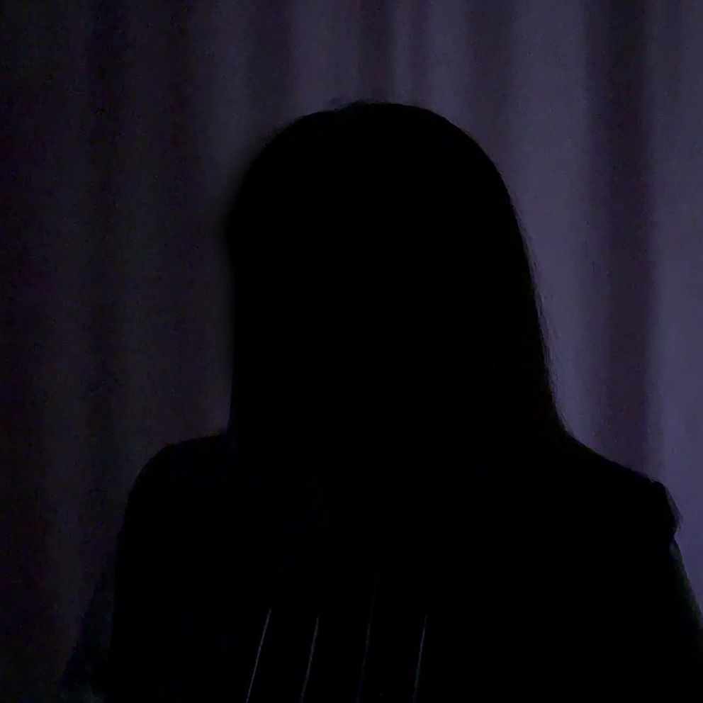 Person i mörker, ansiktet anonymiserat mot bakgrund av ljus gardin.