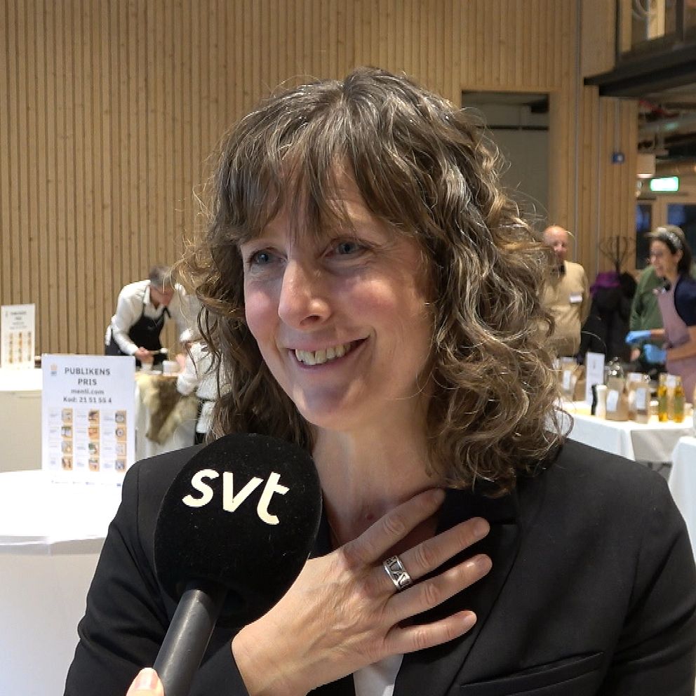 en kvinna ser glad ut och håller handen på sitt bröst
