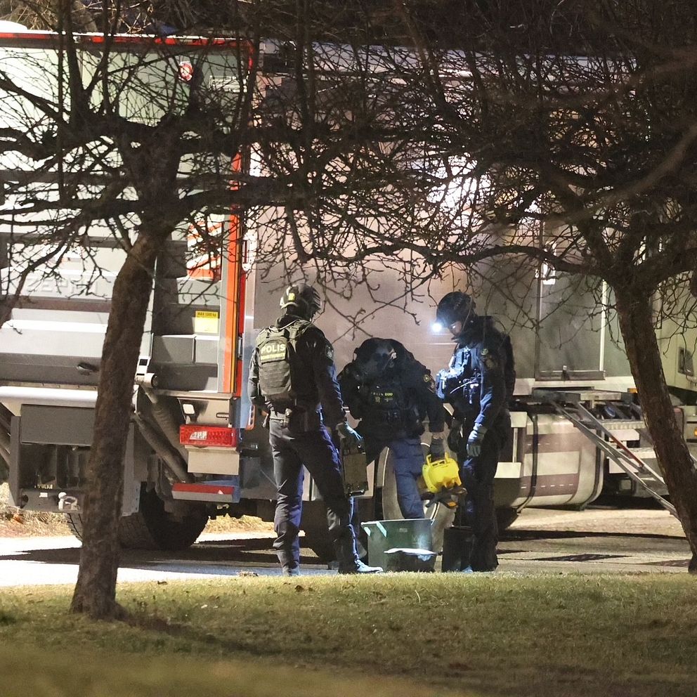 Poliser undersöker föremål, en parkerad lastbil i skymningen.