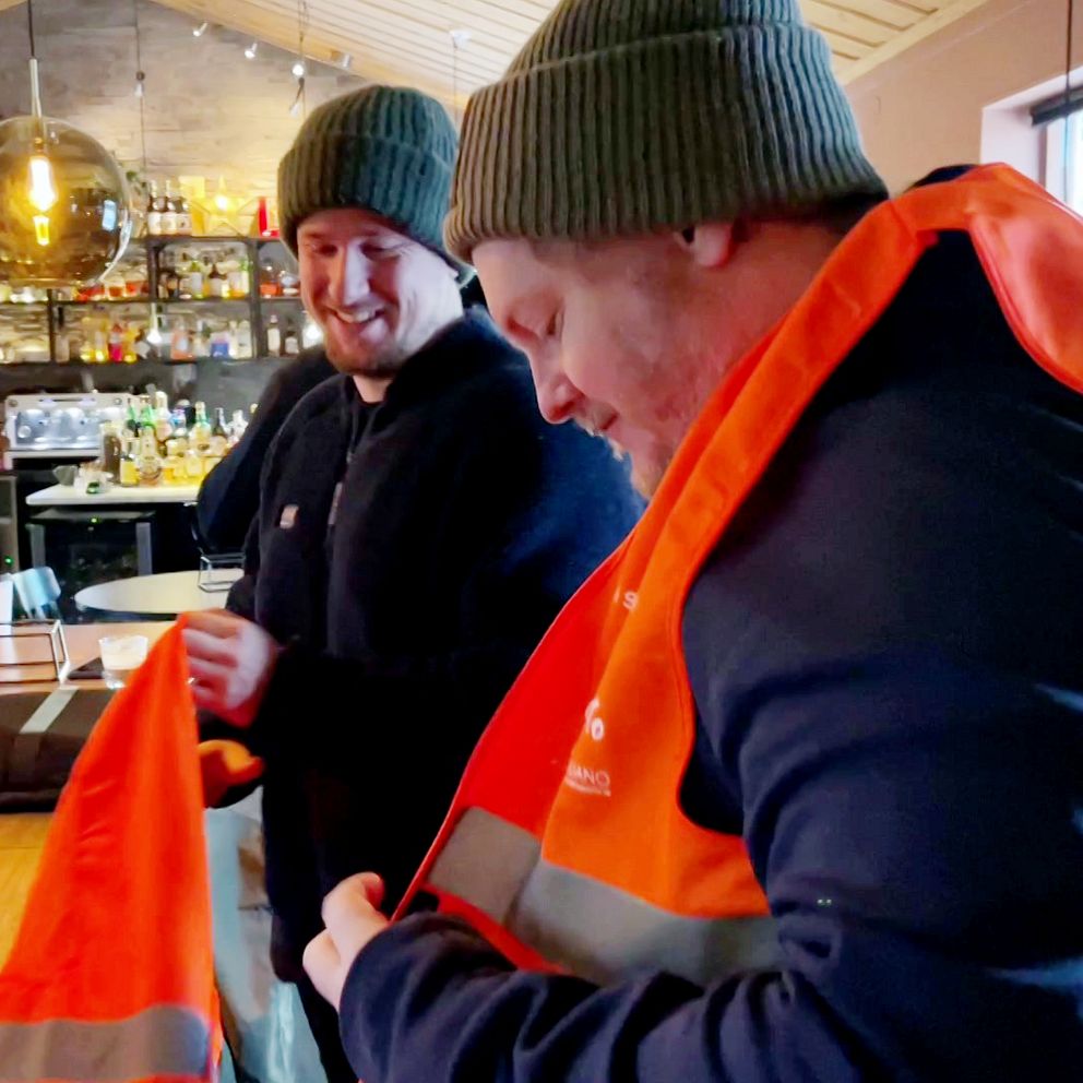 Två personer som står i en bar och har reflexvästar på sig.