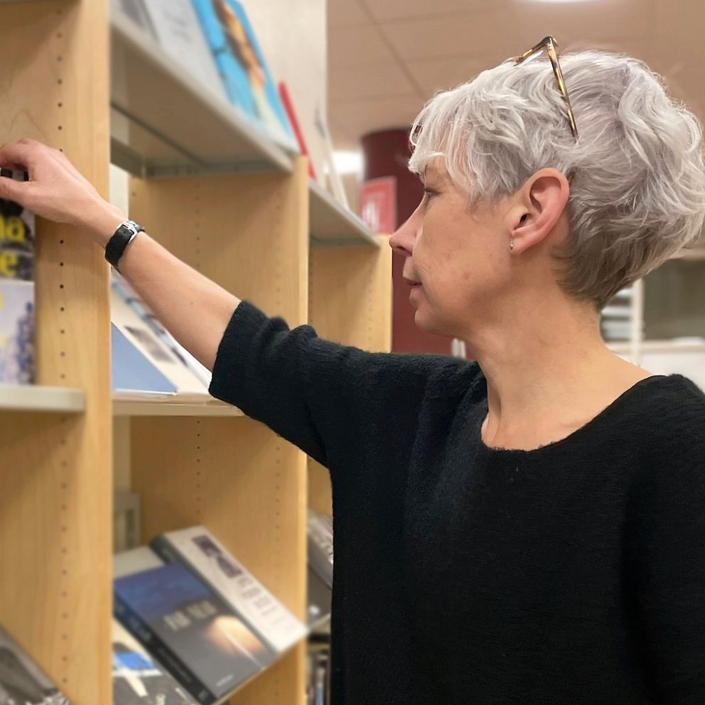 Bibliotekarien Annika Liljengren bläddrar bland fotoböcker på Landskronas stadsbibliotek.