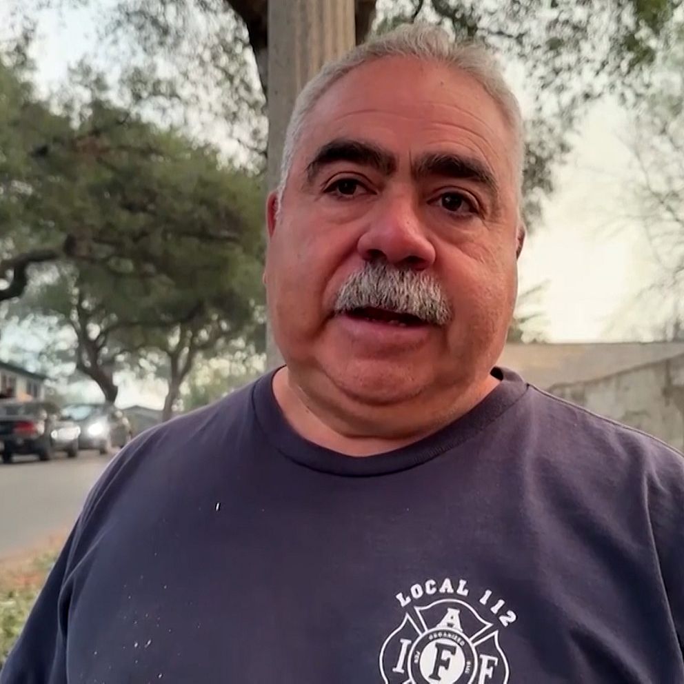 En man i en blå t-shirt med texten ”LOCAL 112” står utomhus, omgiven av träd och en väg.