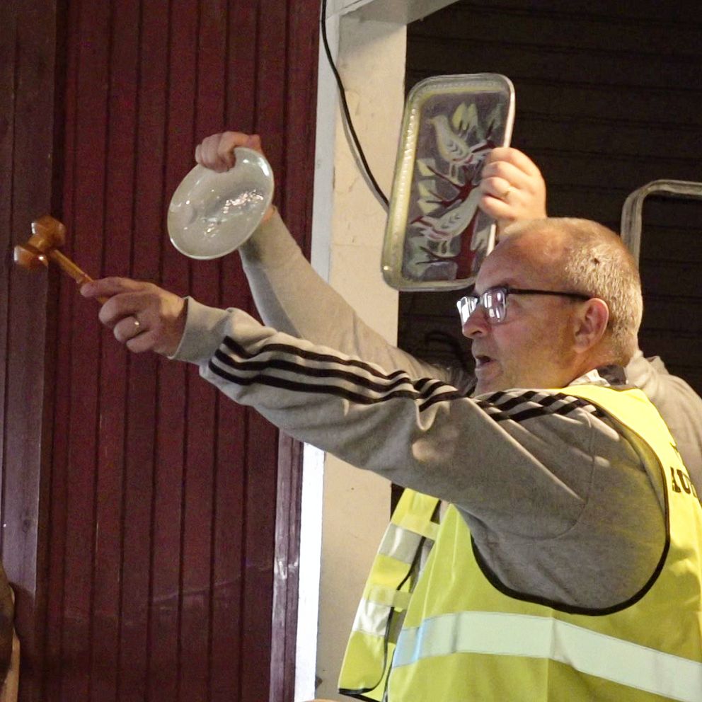 Man i reflexväst auktionerar ut föremål på en auktion