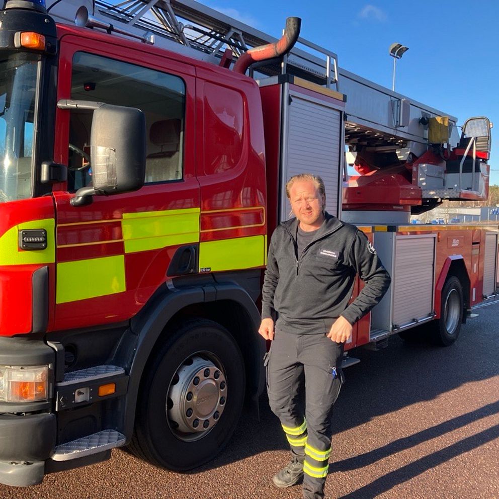 Brandman står framför brandbil