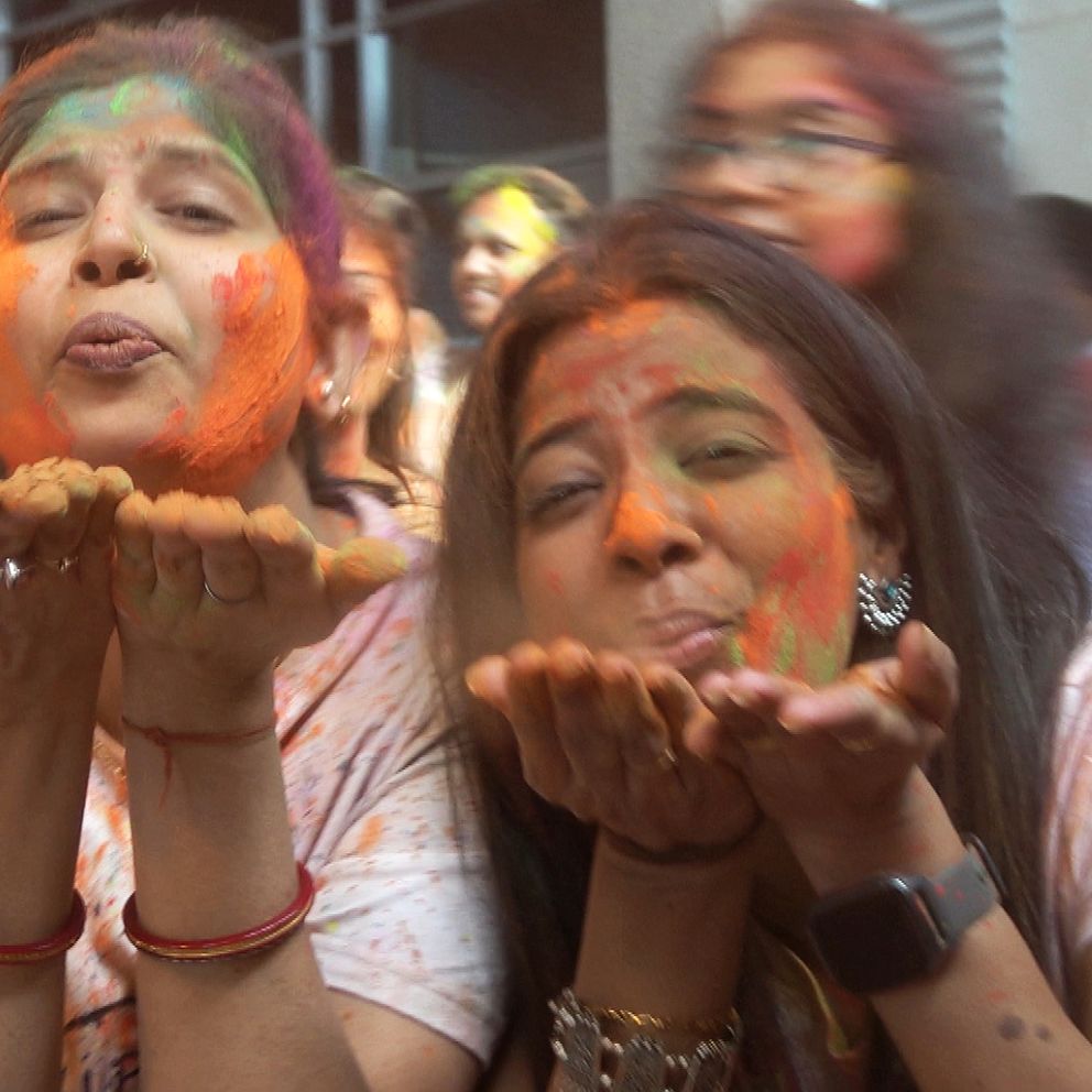 Två kvinnor som blåser färg mot kameran under festivalen Holi i Helsingborg.