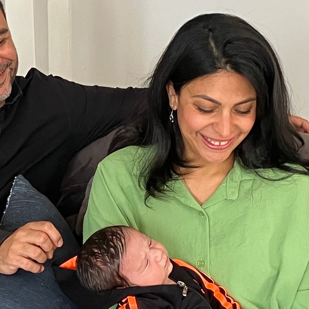 Pappa och mamma med nyfödd bebis i famnen.