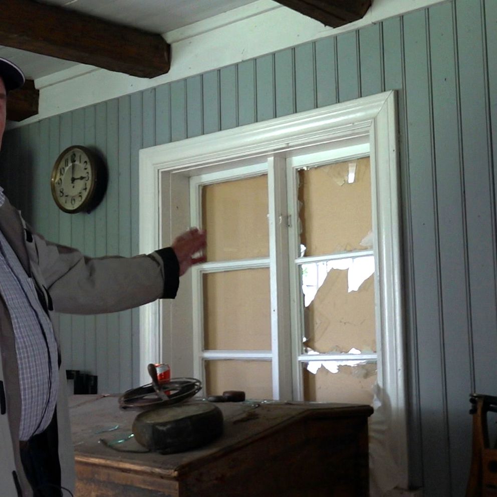 Man tittar på ett trasigt fönster inne i en gammelgård
