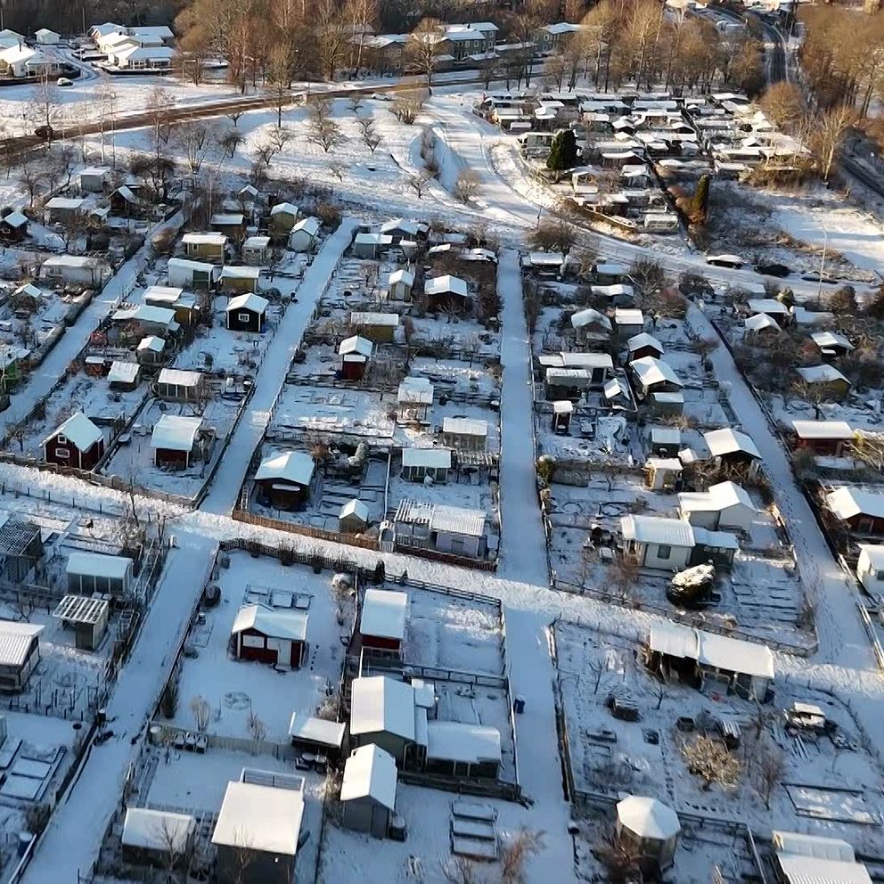 En delad bild med två sektioner. Den vänstra sektionen visar en person i en reflexjacka med gula och grå detaljer, som står utomhus i ett soligt väder. Den högra sektionen visar en fågelvy över ett snötäckt område med radhus och fritidshus, samt träd och bilar, som skapar en lugn vinterlandskap.