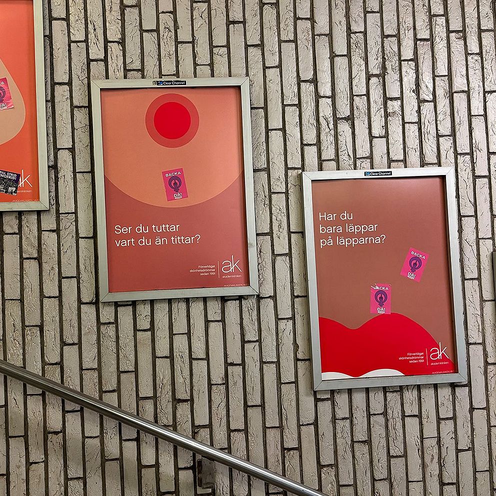 Tre affischer uppsatta på en tegelvägg längs en trappa. Affischerna har enhetliga grafiska designstilar med text som främjar ett budskap.