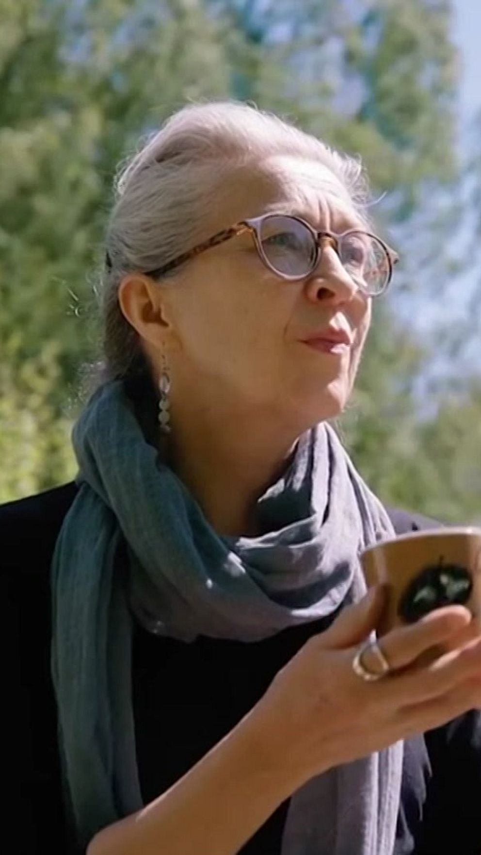 Tove Slotte ulkona kädessään muumimuki, jossa on Haisulin kuva.