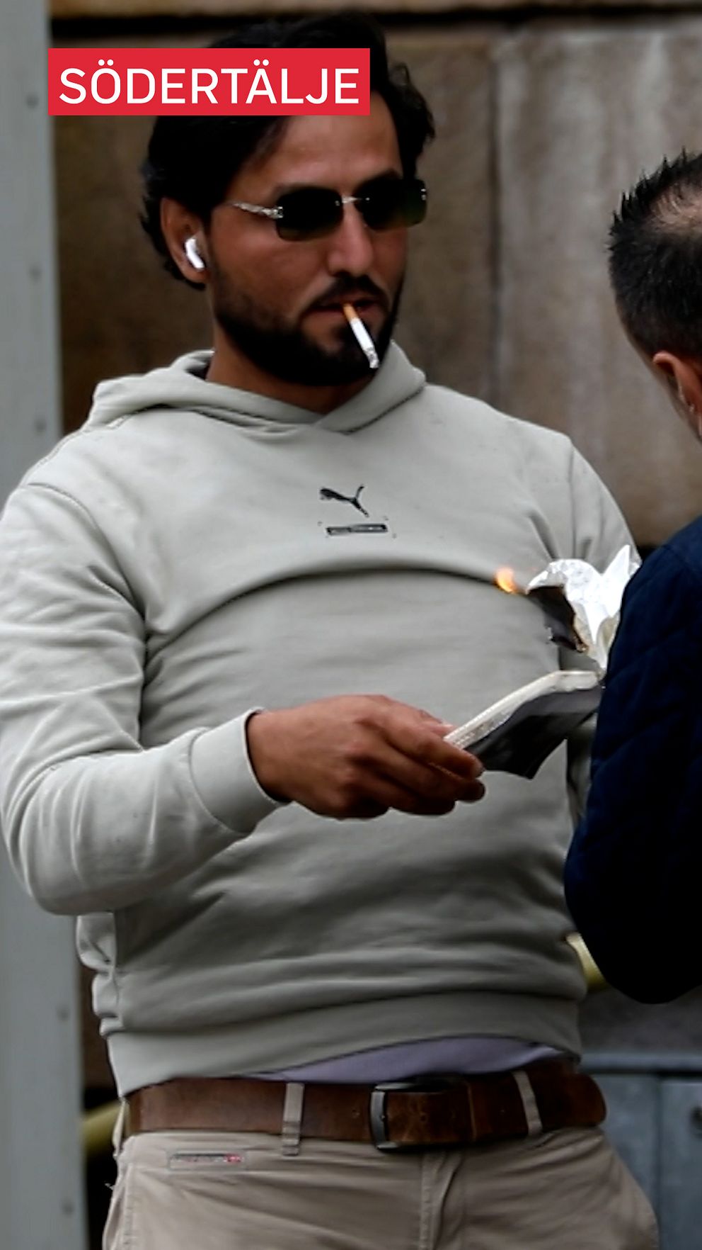 En person i en grå hoodie håller i en brinnande bok.