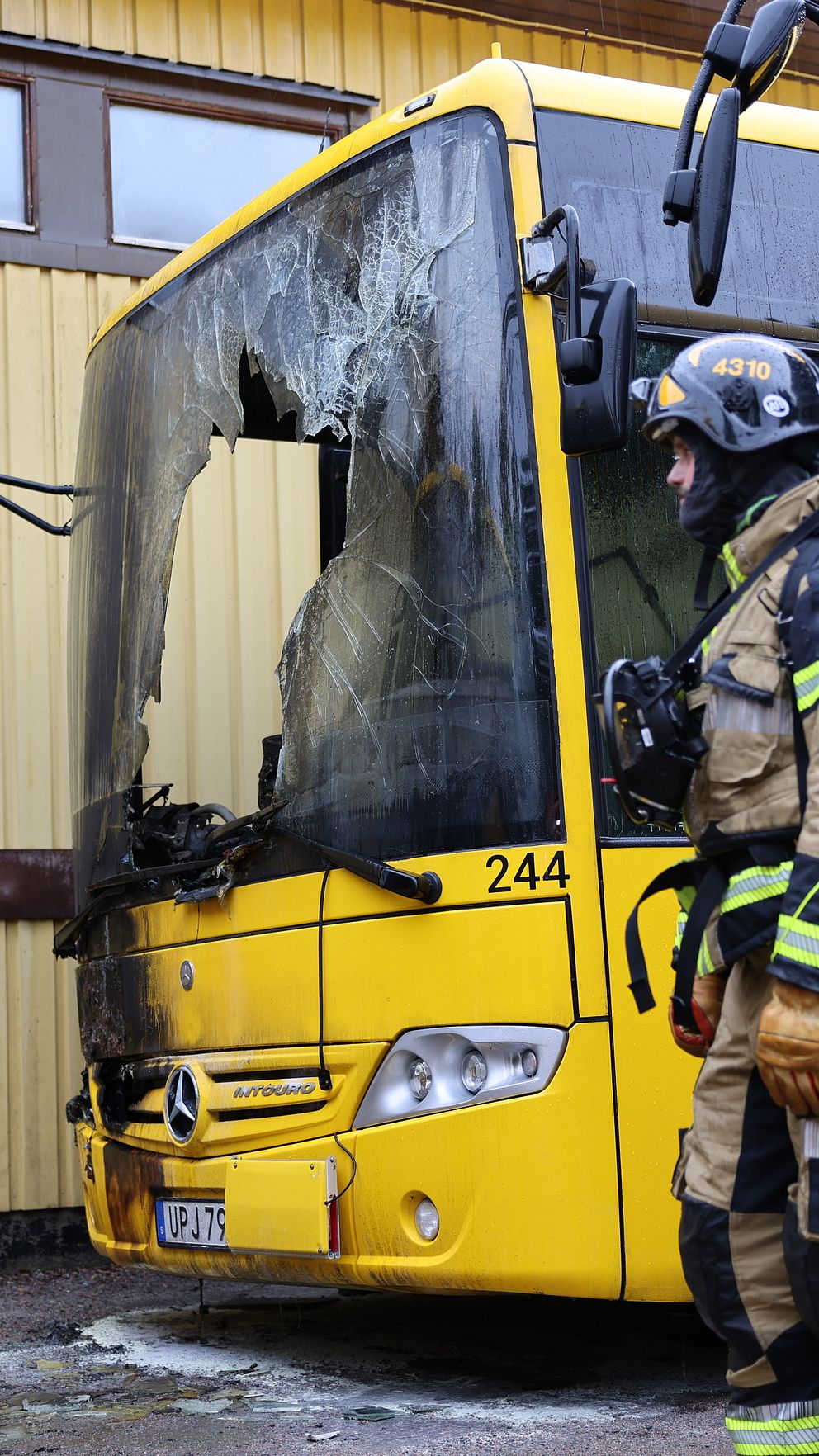 Brandmän vid en utbränd UL-buss på parkering i Alunda