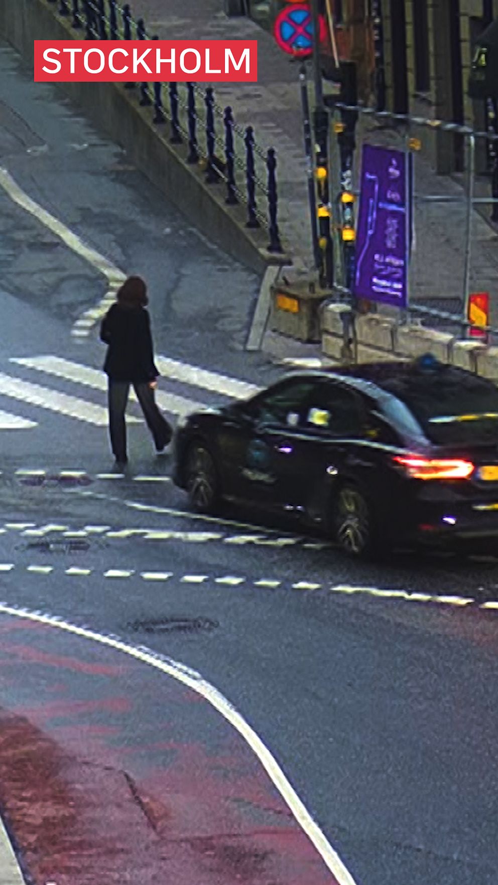 En kvinna går över en gata samtidigt som en svart taxi kör mot henne.