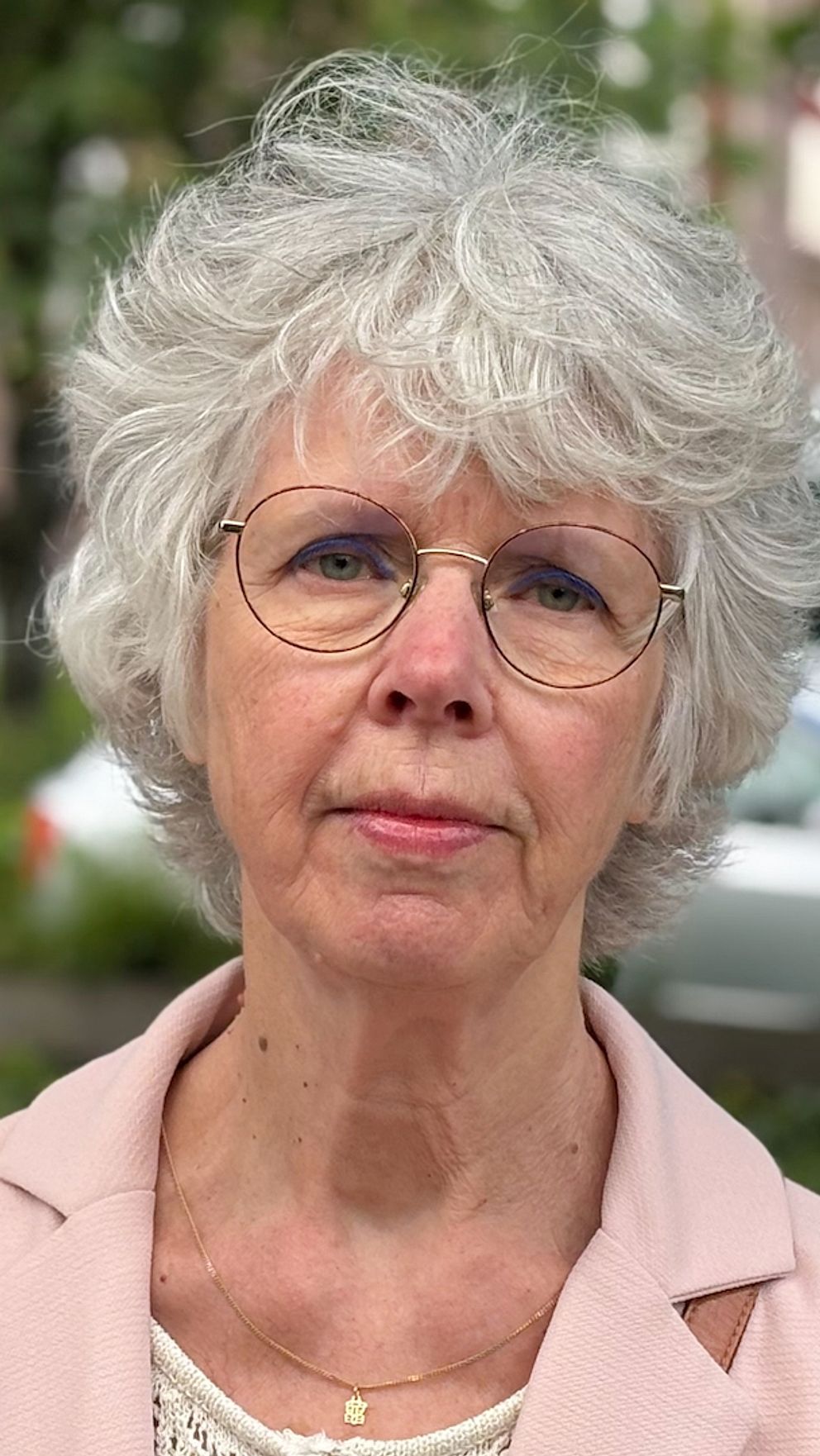 Tina Mangold utomhus i rosa jacka, framför en grönskande bakgrund