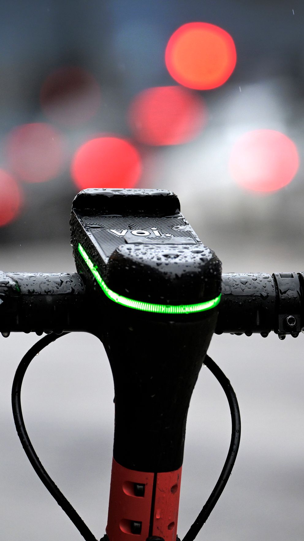Elsparkcykelns styre i förgrunden med suddig stadstrafik i bakgrunden