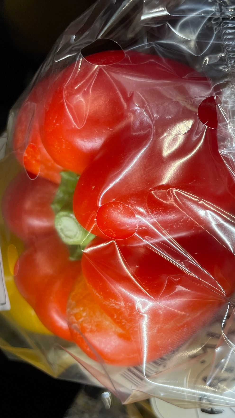 En plastpåse som innehåller röda paprikor